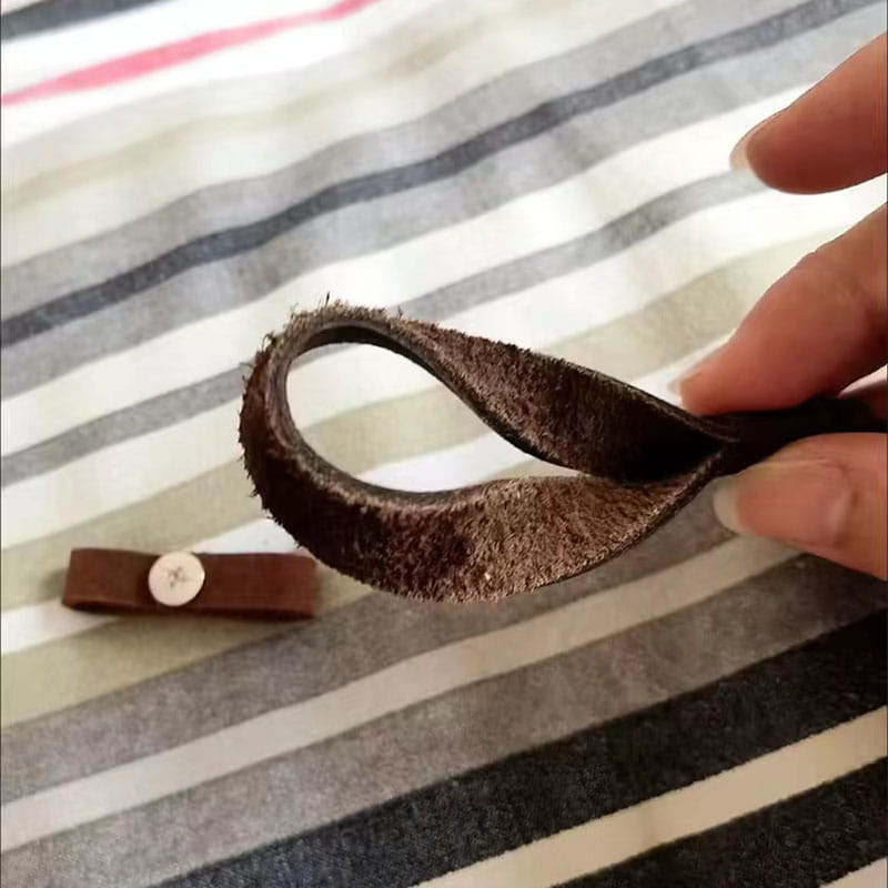 A dark brown slightly worn leather loop with a soft suede-like texture and frayed edges on a leather weave lanyard keychain car key holder.