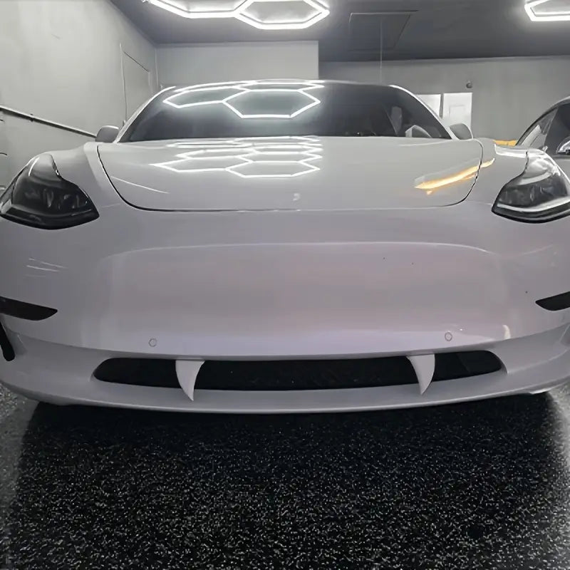 Weißer Tesla Model 3 mit glänzender Oberfläche und markantem Frontgrill-Design, mit Halloween-Vampirzahn-Autotaufklebern aus Kunststoff-Monsterfängen.