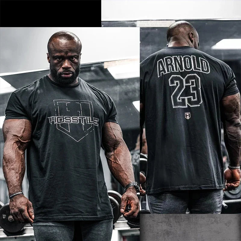 Schwarzes Herren-Cotton-Fitness-T-Shirt für Activewear mit kurzen Ärmeln und Darstellung der Rückseite, mit weißer Aufschrift Arnold 23 und einem Wappensymbol auf der Vorderseite.