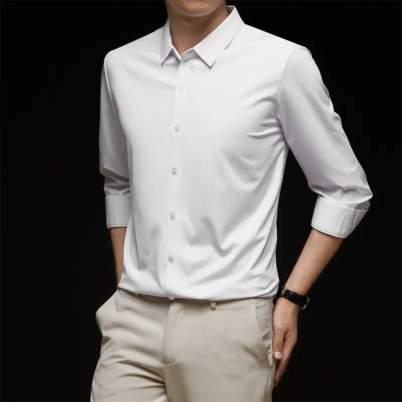 Una camisa de vestir para hombre sin arrugas blanca e impecable, con mangas largas, cuello clásico y parte delantera abotonada.