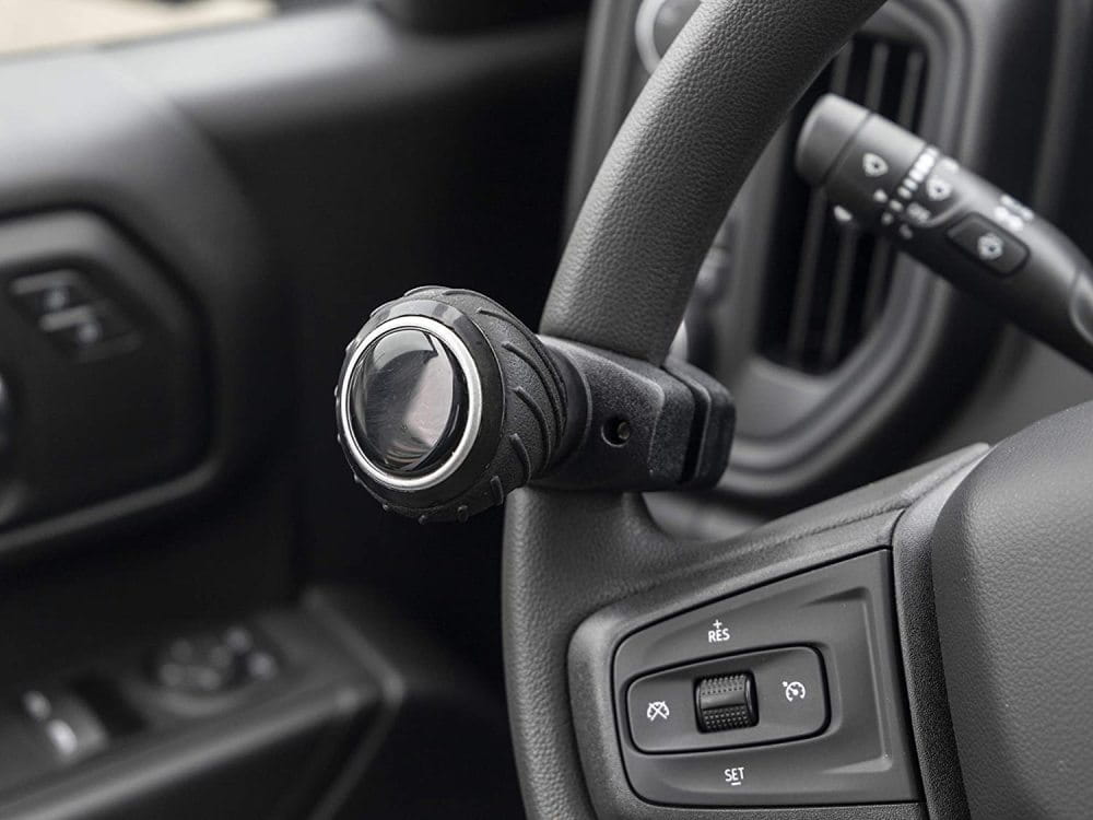 Perilla giratoria para volante texturizada negra con empuñadura ergonómica y anillo metálico plateado de acento diseñada para un cambio de marcha fácil.