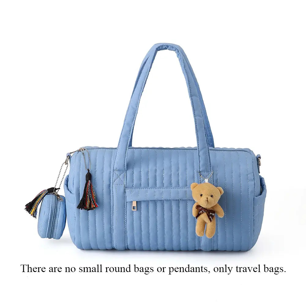 Eine hellblaue gepolsterte Kinderwagen-Organizer-Tasche mit einem kuscheligen Teddybär-Anhänger und Akzenten mit Quasten für eine praktische Aufbewahrung auf Reisen.