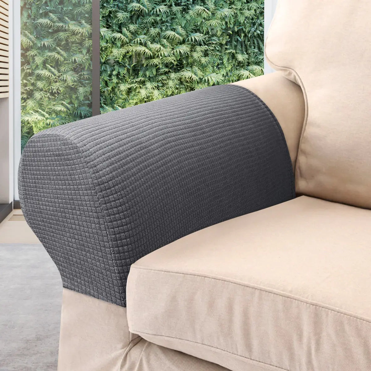 Dunkelgraue wasserabweisende Stretch-Abdeckung für die Armlehne aus geripptem Spandexstoff, die eng über die geschwungene Armlehne eines beigen Sofas passt.