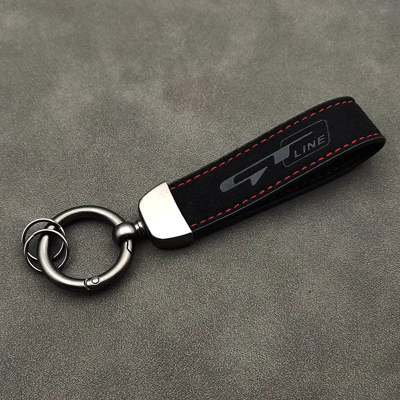 Schwarzer Wildleder-Lederschlüsselanhänger der GT Line mit roter Steppnaht und einem silbernen Logo, das eine Metallring-Anbringung zeigt.