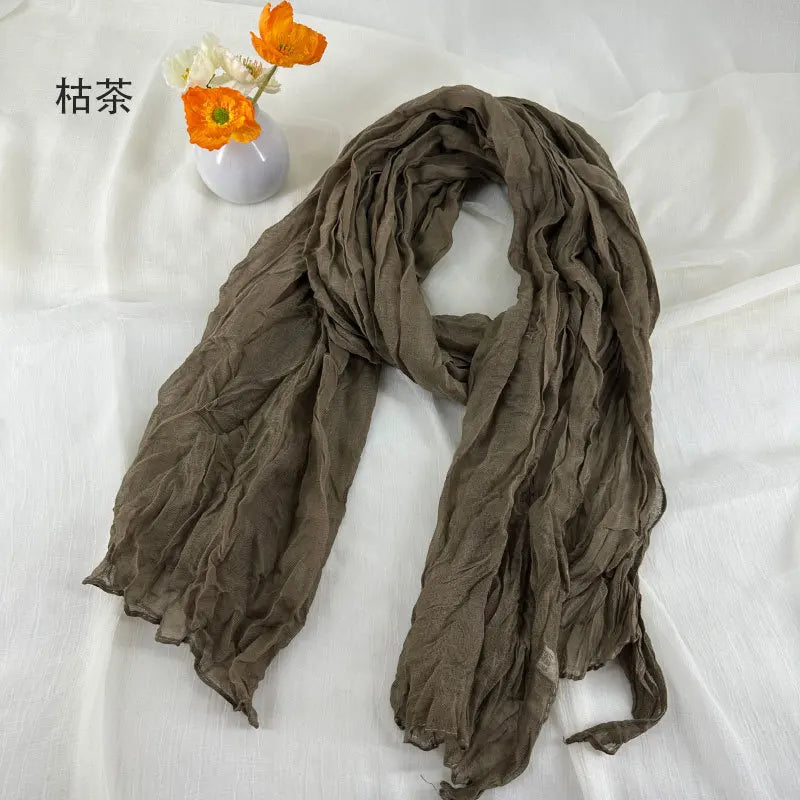 Écharpe en coton et lin plissé marron, douce et froissée, avec une texture légère et fluide.