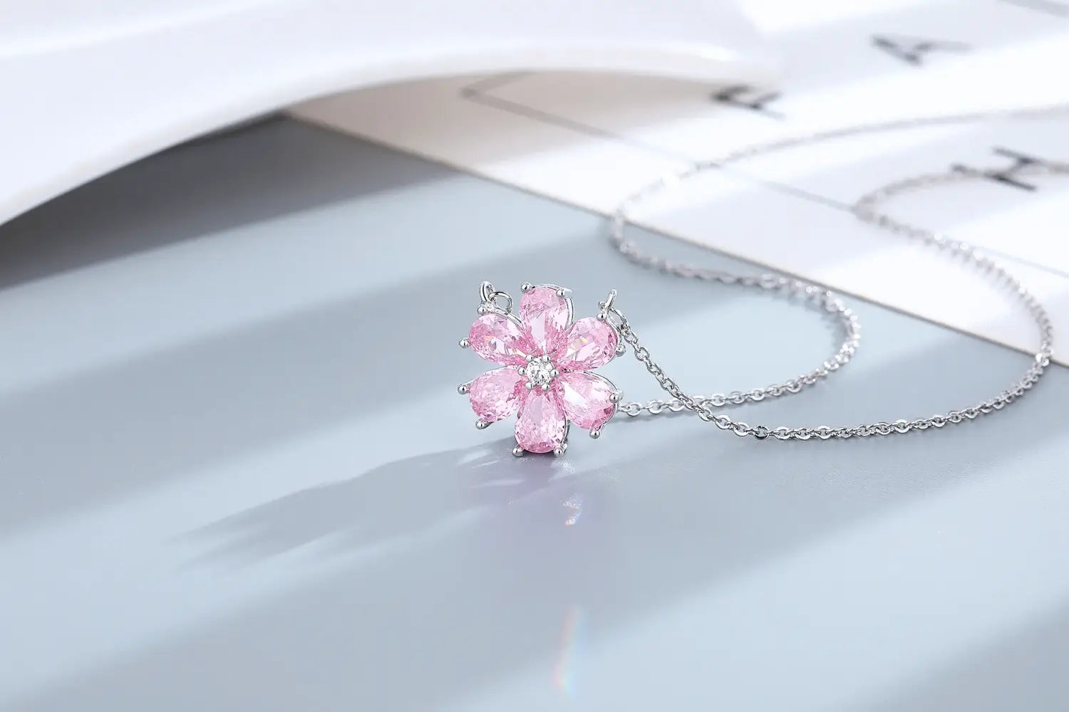 Eine zarte Halskette mit Anhänger in Form einer pinkfarbenen Kirschblüte mit Silberkette aus dem Schmuckset „Silber Pink Kirschblüte“.