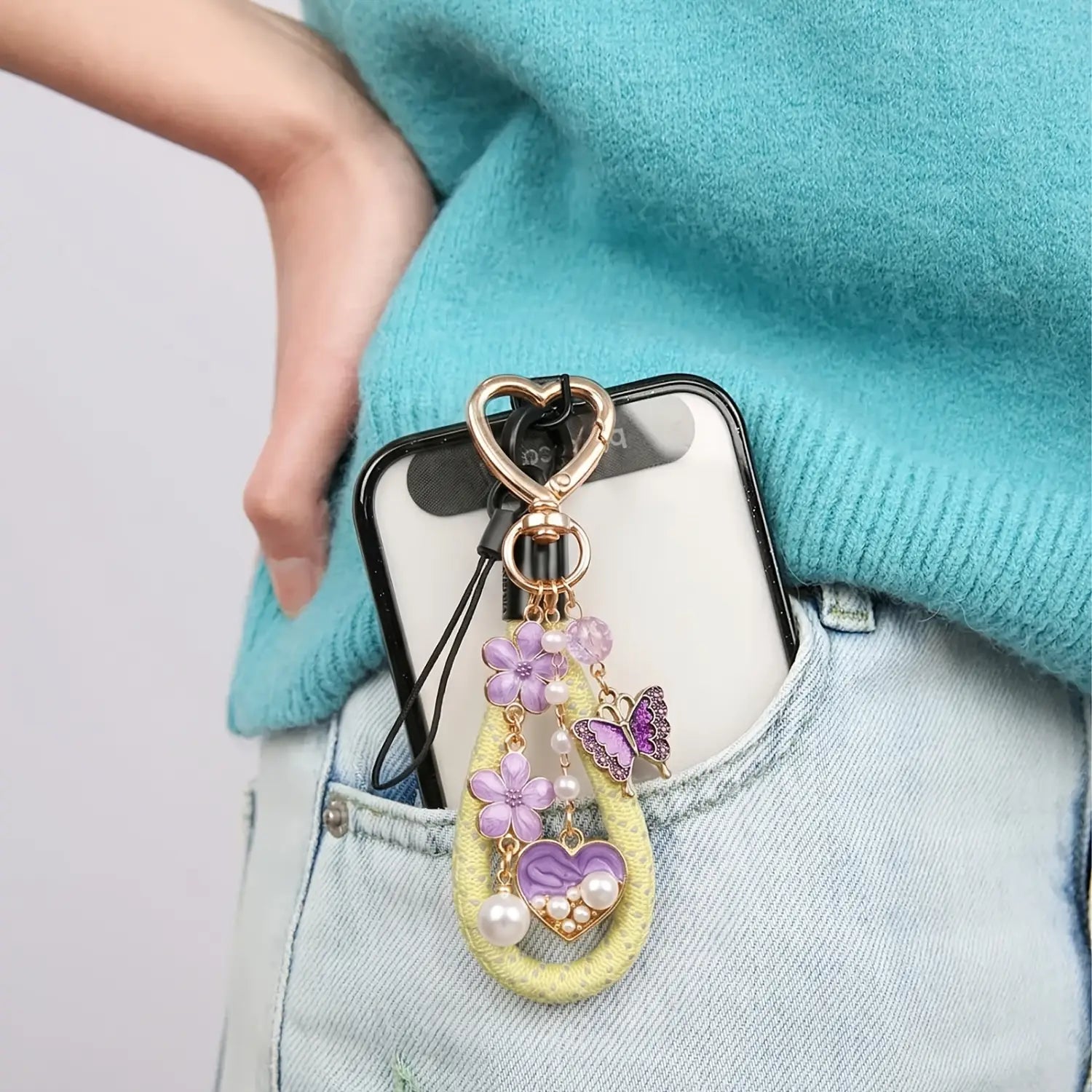 a delicate lavender and gold enamel phone charm with floral butterfly and heart motifs on a yellow woven strap featuring a gold heart clasp ring from the heart keychain 3pack collection