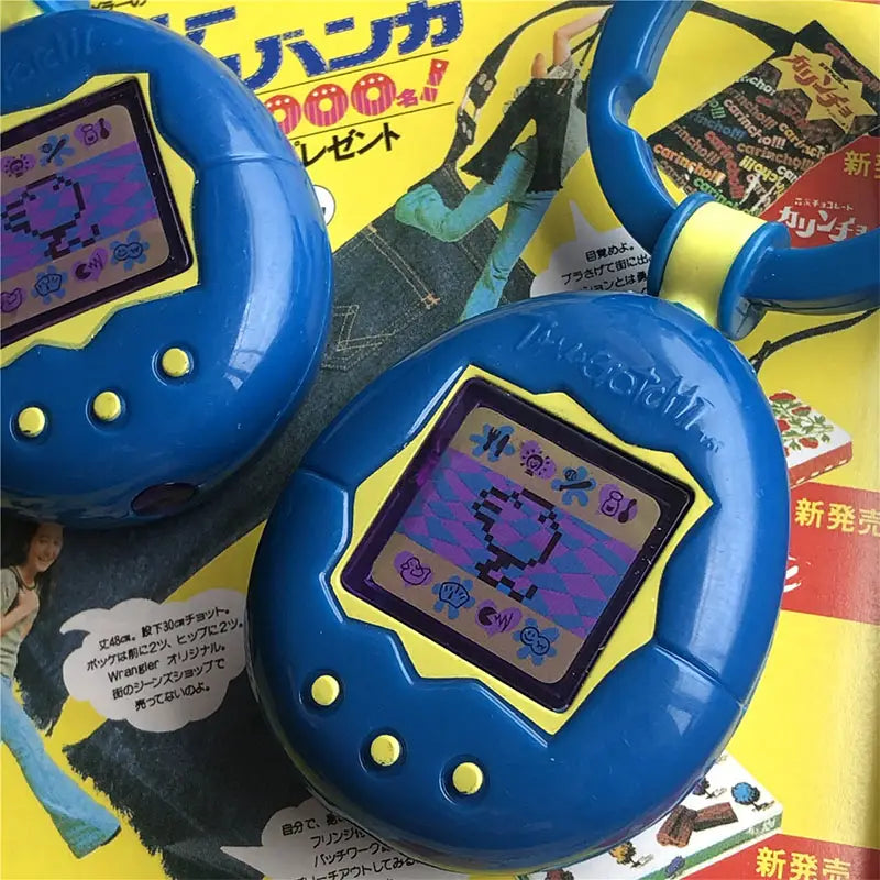 Blue and yellow tamagotchi electronic virtual pet keychain with a pixelated screen displaying a digital creature, a 90s toy.