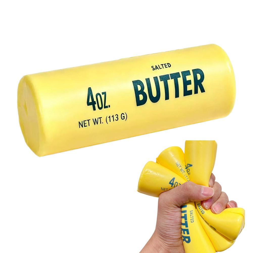 yellow butter stick slow rising squeeze toy wrapped in a cylindrical plastic wrapper with bold green lettering and weighing 4 oz
