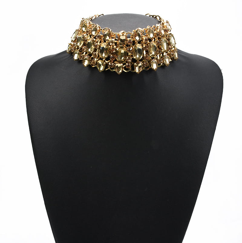 Un collier ras du cou doré présentant plusieurs rangées de pierres translucides de couleur ambre, facettées, montées sur une armature métallique pour un port élégant.