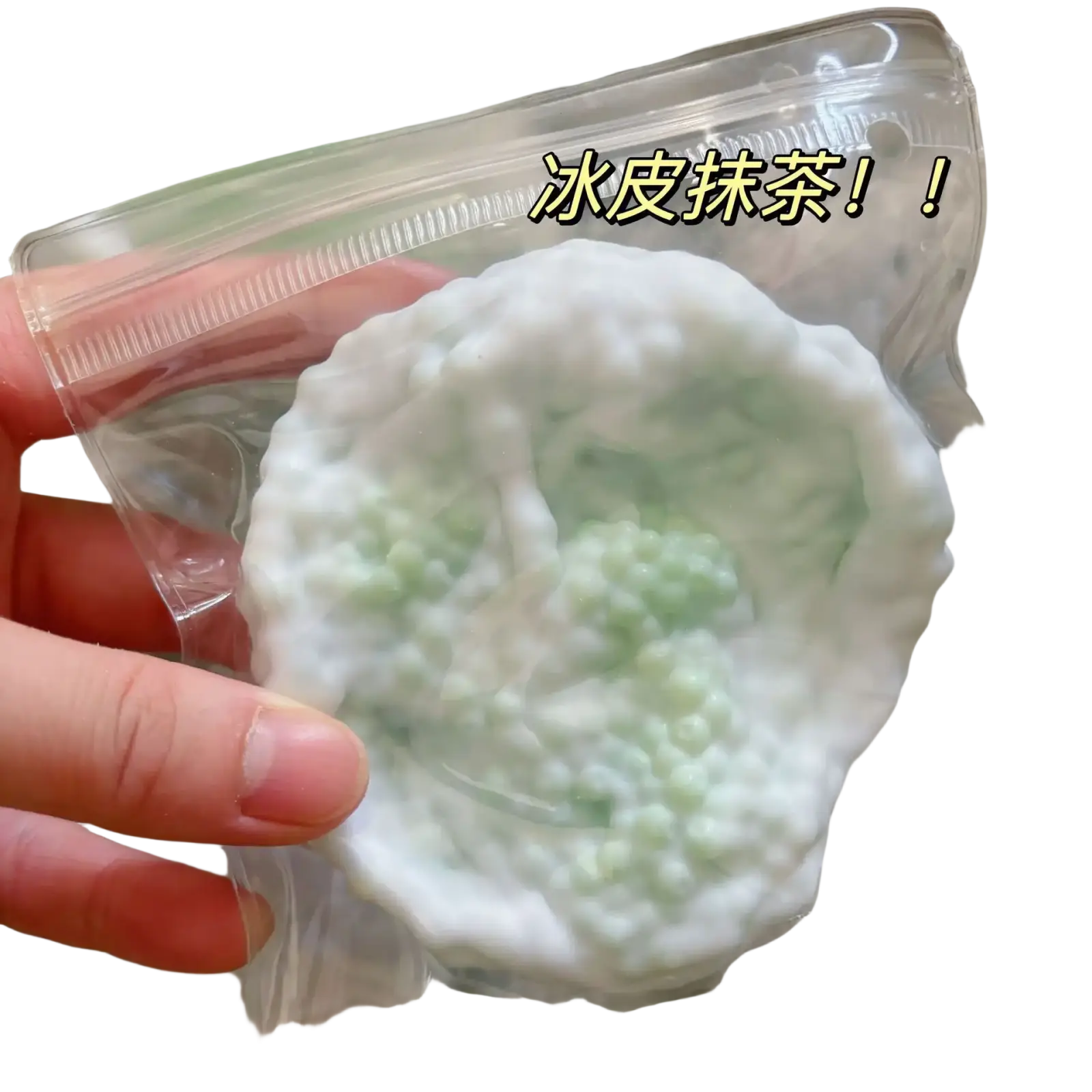 un récipient en plastique translucide contient une boule blanche et vert clair de jouet anti-stress souple en peau de neige à base de sel de mer, ressemblant à un dessert glacé, avec des perles de tapioca visibles.