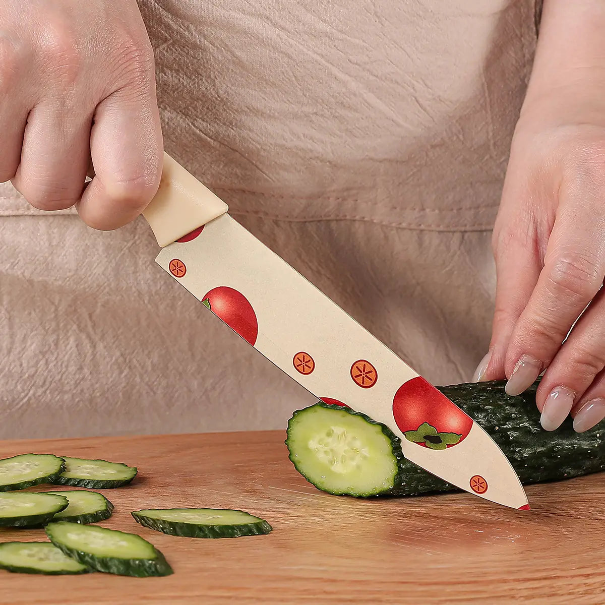 A ceramic kitchen knife with a beige handle and blade decorated with red tomato illustrations and orange starburst accents from the ceramic kitchen knife set tomato pattern.