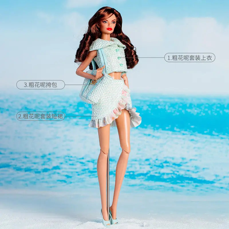 1／6スケールドール用ドレス小物アクセサリーとギフトセット。ライトブルーのツイードのクロップドトップと、同系色のフリル付きミニスカートを着用したバービー人形。コーディネートされたライトブルーのツイードのショルダーバッグを持っている。