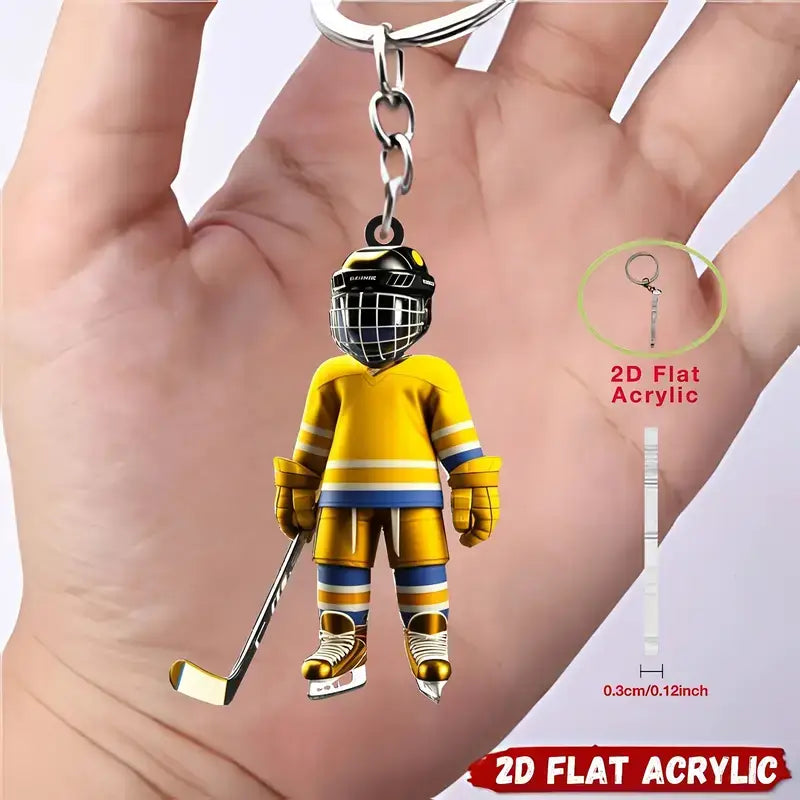 A yellow and blue hockey goalie acrylic keychain featuring a detailed helmet with black face cage and gold accents designed as a sports backpack charm.