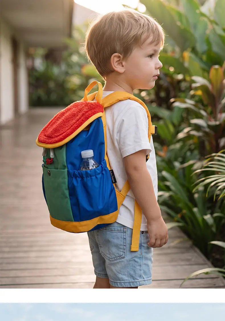 Ein lebhaftes mehrfarbiges leichter Fuzzy-Rucksack für Kinder mit rotem Fleece-Oberteil und gelber Verzierung, entworfen für die Verwendung als Kindergartentagesrucksack.