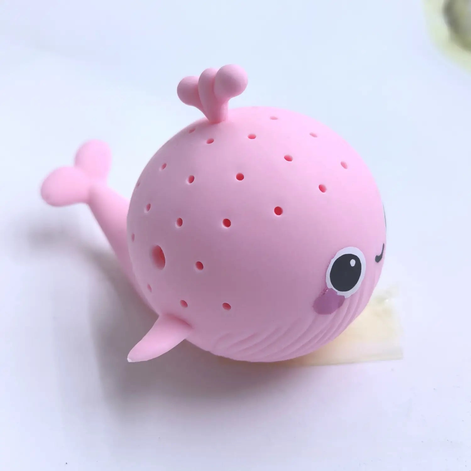 Ein pinkfarbener Silikon-Blauwal geformter Teeei-Aufgussbehälter mit niedlichen Gesichtszügen und einem perforierten Körper, gestaltet als Blauwal-Badeschwamm-Wasser-Spielzeug für Kinder.