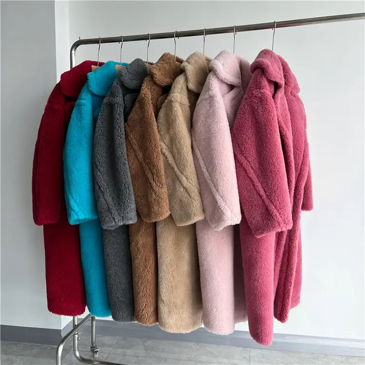 Colección de abrigos exteriores tipo osito de peluche largos para mujer de lana en colores vibrantes, incluidos rojo, azul, gris, marrón, beige, rosa y coral, colgados ordenadamente en una estructura metálica, destacando el servicio de atención al cliente para mediciones precisas del contorno de pecho y del contorno de cadera.