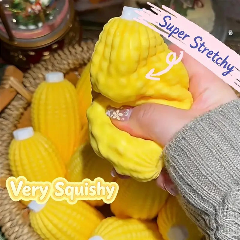 Jouet sensoriel de type balle anti-stress en forme d’arachide en forme de maïs, jaune vif, super extensible et très souple, avec un capuchon blanc.