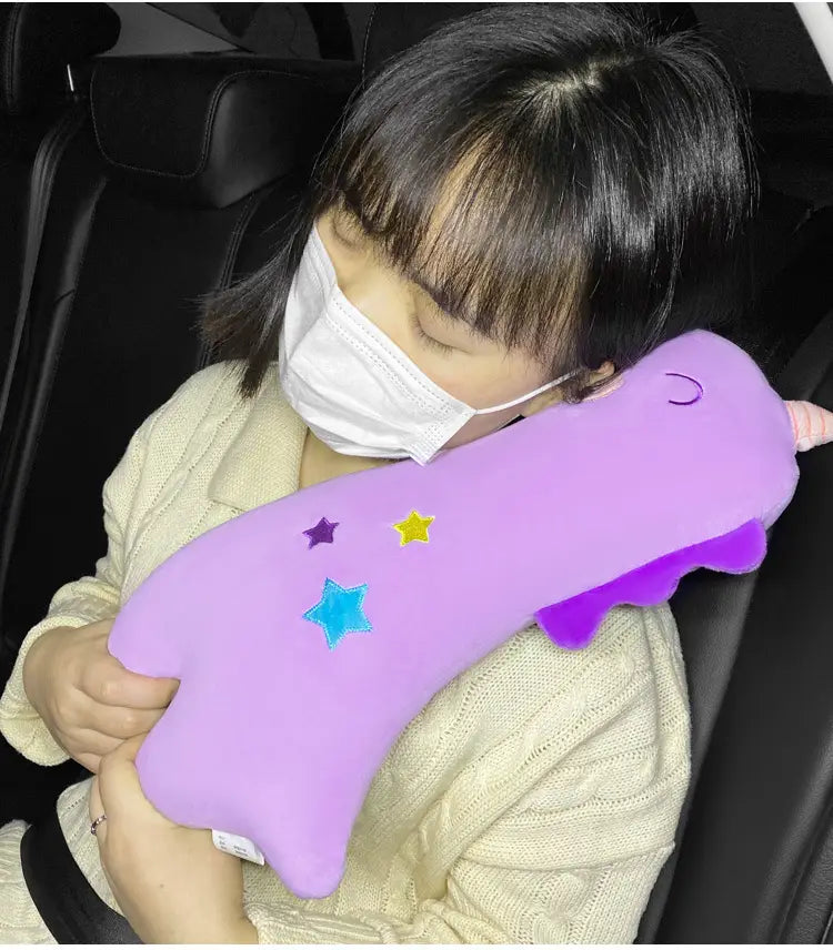 Lila Plüsch-Einhorn-förmiges Nackenkissen mit bestickten Sternen und einem kleinen Horn, ausgelegt als Autositzgurtkissen für Kinder.