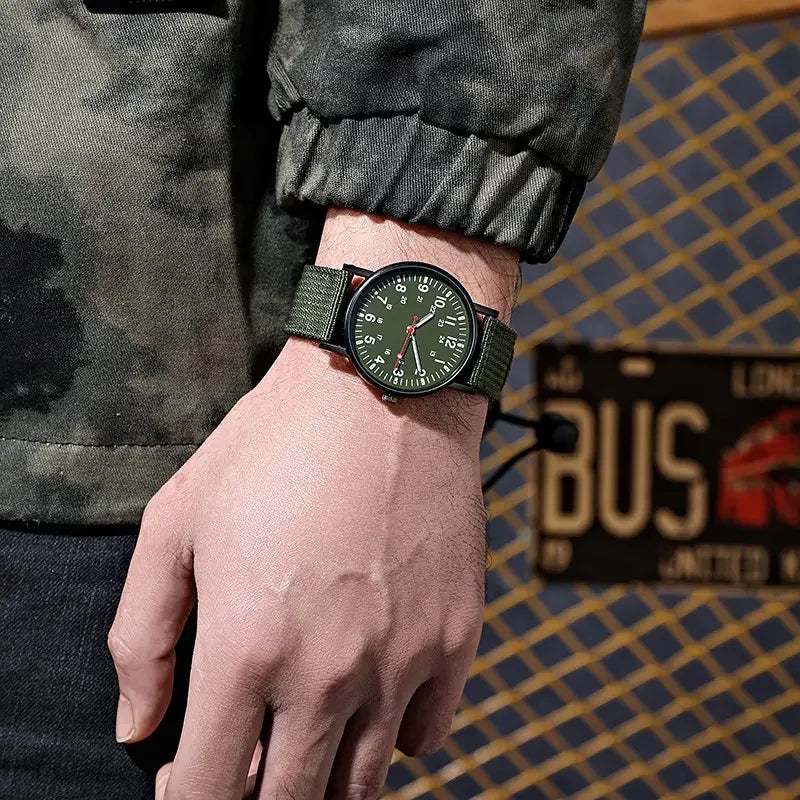Militärisches Quarzarmbanduhr mit olivgrünem Nylonarmband und schwarzem Zifferblatt mit weißen Ziffern.