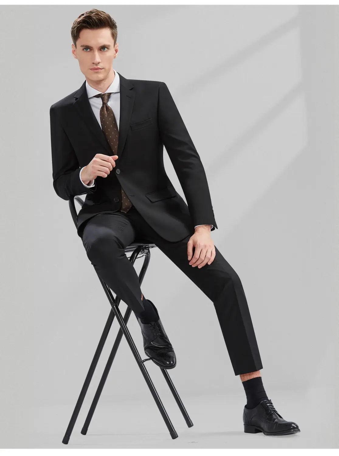 Costume noir pour homme en coupe slim, parfaitement taillé, avec type de fermeture boutonnée simple, comprenant une veste formelle professionnelle décontractée et un pantalon assorti.