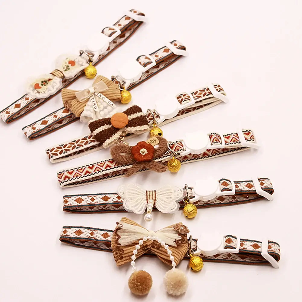 adjustable floral cat collar with bell featuring cute beige and brown patterned fabric decorated with bows and small golden bells or pom-poms with adjustable length for comfortable fit
