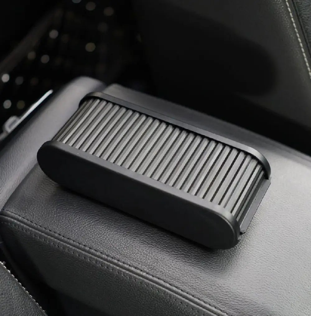 Black plastic car dashboard organizer with lid and coin holder featuring a ribbed textured surface.
