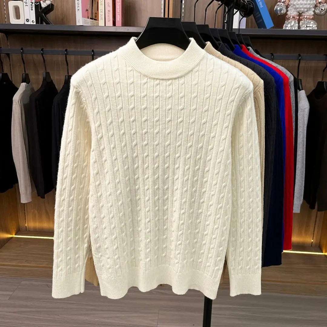 Herren-Zopfstrick-Pullover mit Rundhalsausschnitt in Cremefarben mit geripptem Rundhalsausschnitt und langen Ärmeln, dargestellt auf einem schwarzen Kleiderbügel.