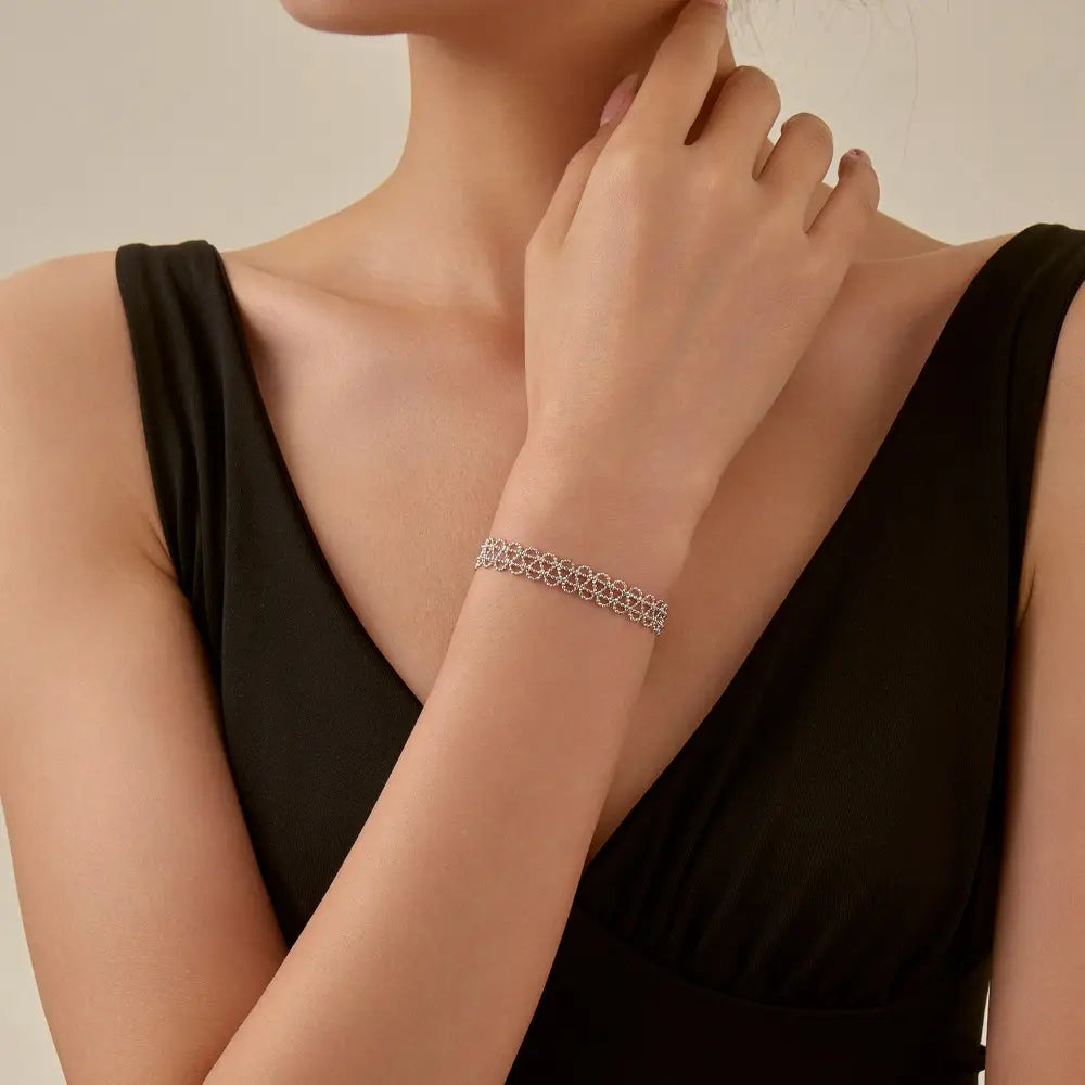 A delicate silver-toned adjustable metal lace bracelet featuring an intricate repeating geometric pattern.