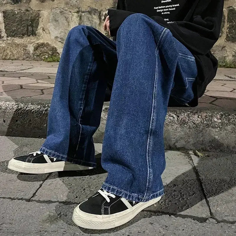 Jeans en denim bleu foncé à jambes larges pour hommes, avec un style streetwear coréen ample et des surpiqûres visibles.