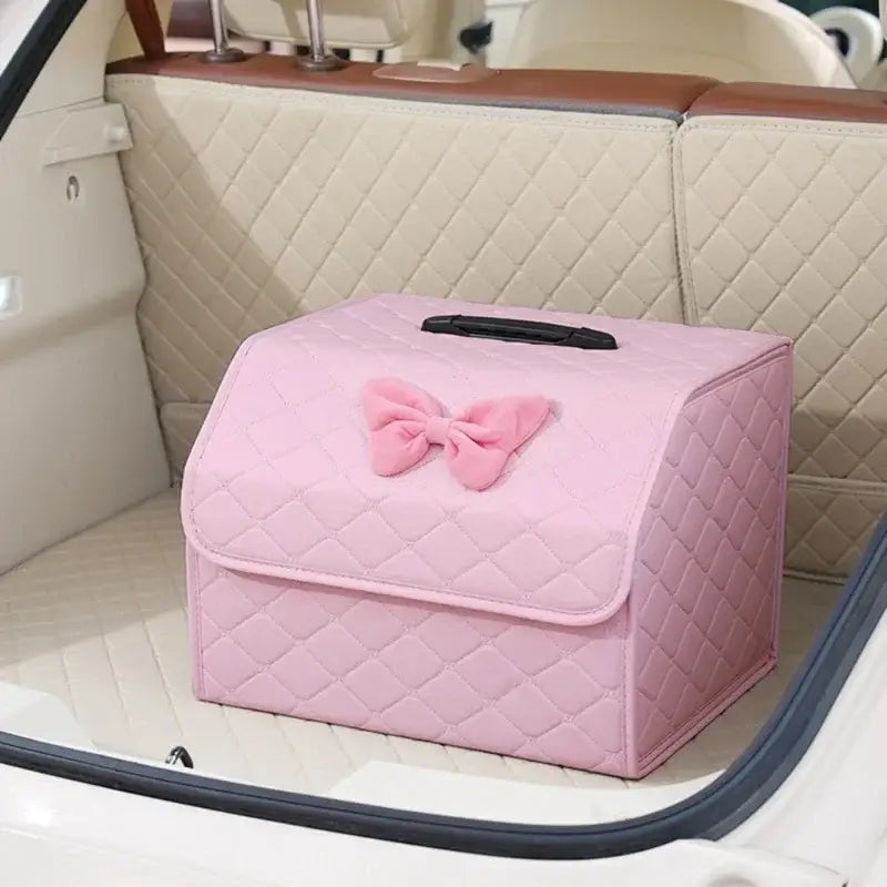 Pink quilted car trunk organizer made of plush material featuring a decorative bow on top.