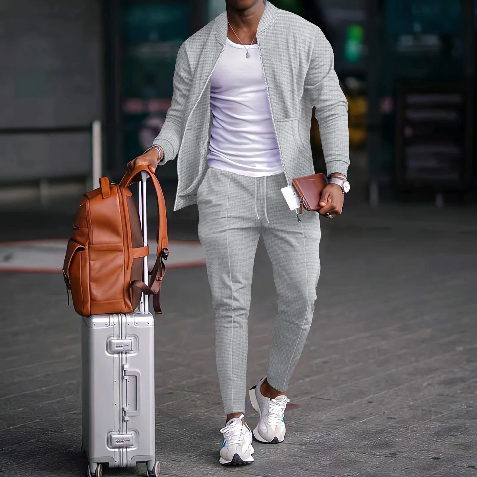Una maleta elegante de aluminio plateado con asa retráctil y ruedas resistentes, mostrada junto con un conjunto informal de deporte tipo gofre para hombre