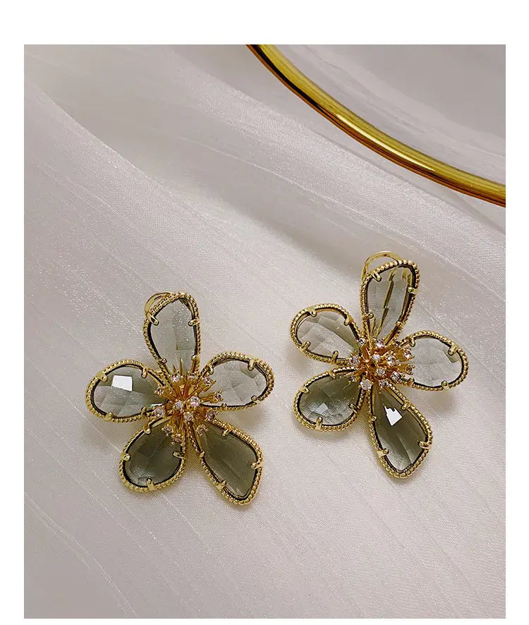 ファセットカットのスモーキークォーツの花びらと、きらめく中心部を備えた、繊細なゴールドフラワークリスタルスタッドピアス。