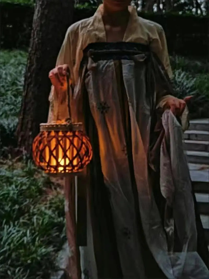 Un porte-bougie en bambou tissé, lumineux et chaleureux, avec une lumière intérieure orange, conçu pour la décoration intérieure du domicile.