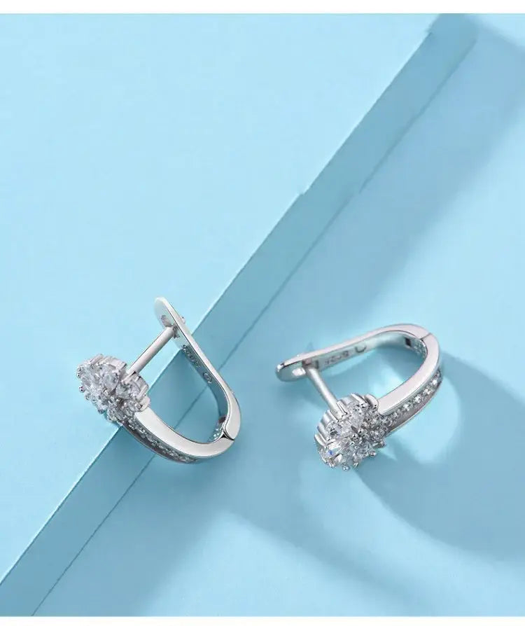 Los pendientes de flores de circonio en plata de ley presentan un diseño de aro plateado adornado con cristales claros y brillantes en un patrón floral.