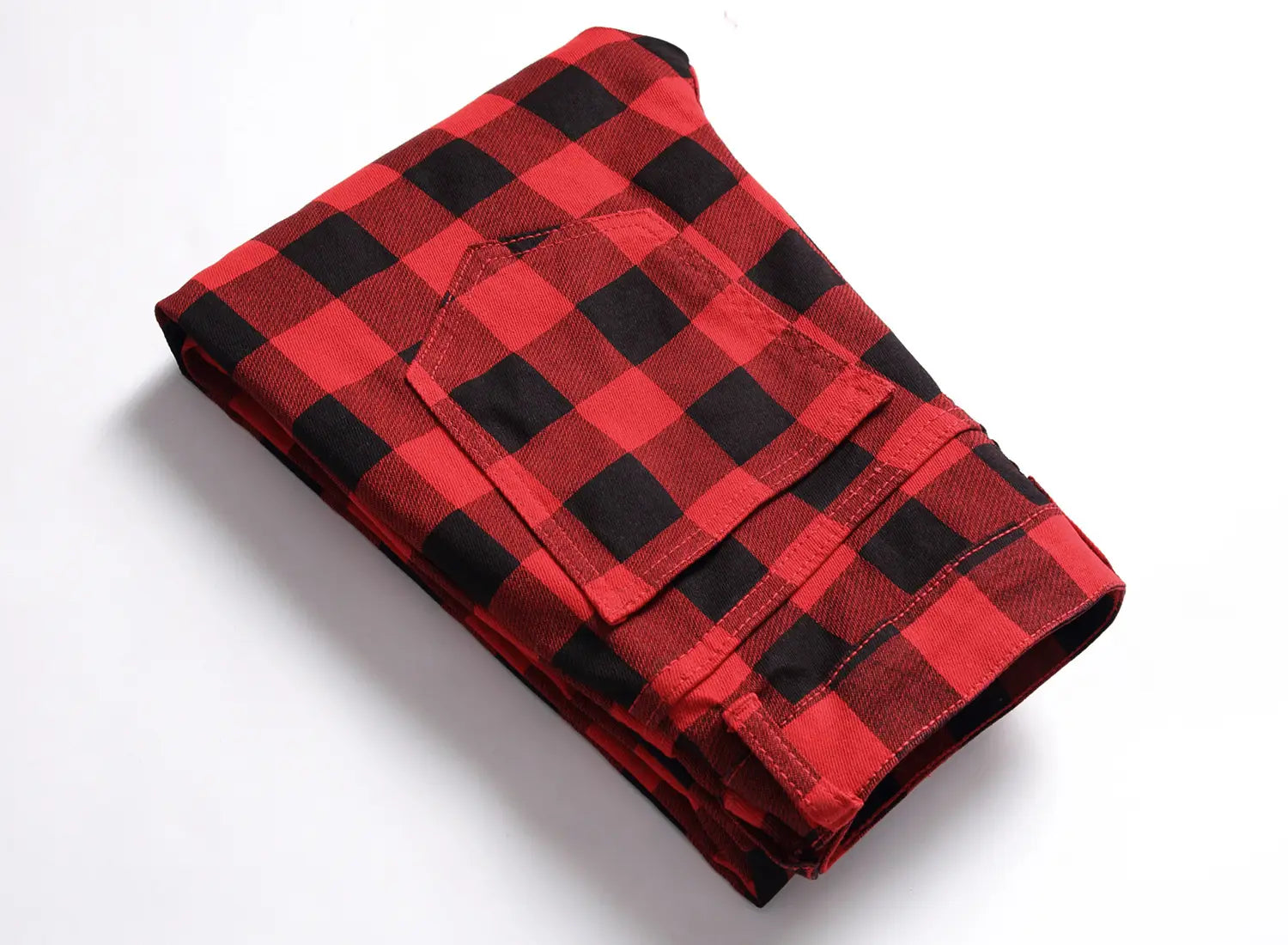 Jeans en denim rouges à carreaux, coupe slim ajustée, en tissu à carreaux rouge et noir, plié pour mettre en évidence une poche avant.