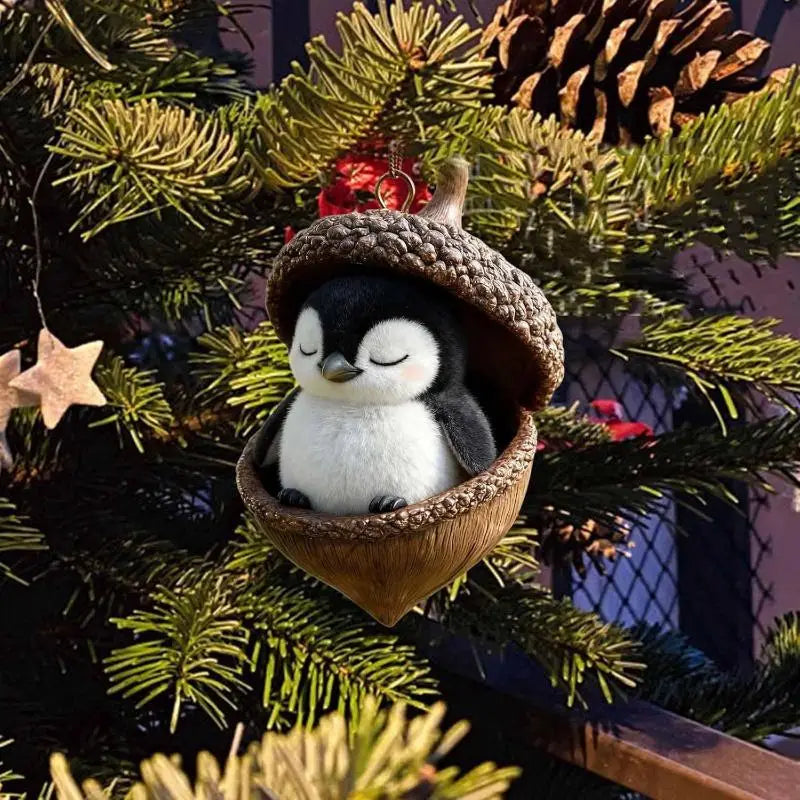 黒と白の愛らしいぬいぐるみのペンギンが、質感のあるこげ茶色のどんぐり形のアクリル製クリスマスオーナメントの中に収まっています。クリスマスツリーに掛けて、動物クリスマスオーナメントの装飾の一部として飾られます。