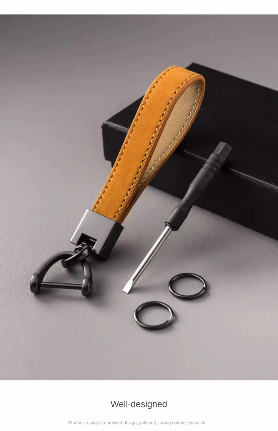 A genuine leather car keychain in sleek mustard-yellow suede with a black metal d-ring and matching hardware featuring precise edge stitching.