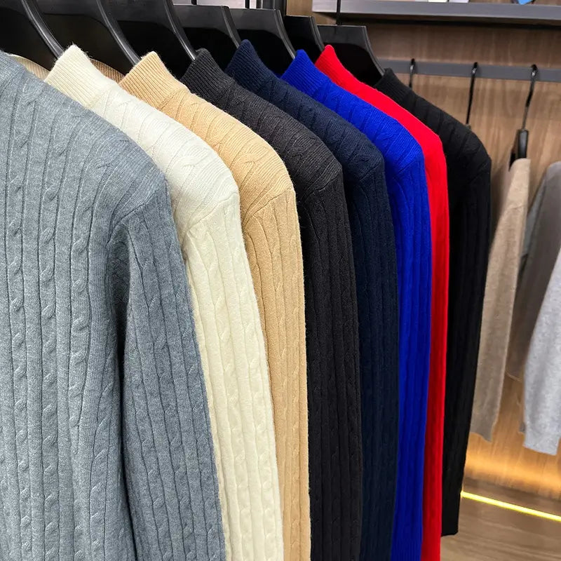 Eine Reihe von Herren-Zopfstrick-Pullovers mit Rundhalsausschnitt in einfarbigen Farben Grau, Creme, Beige, Navyblau, Königsblau und Rot aus gestricktem Material.