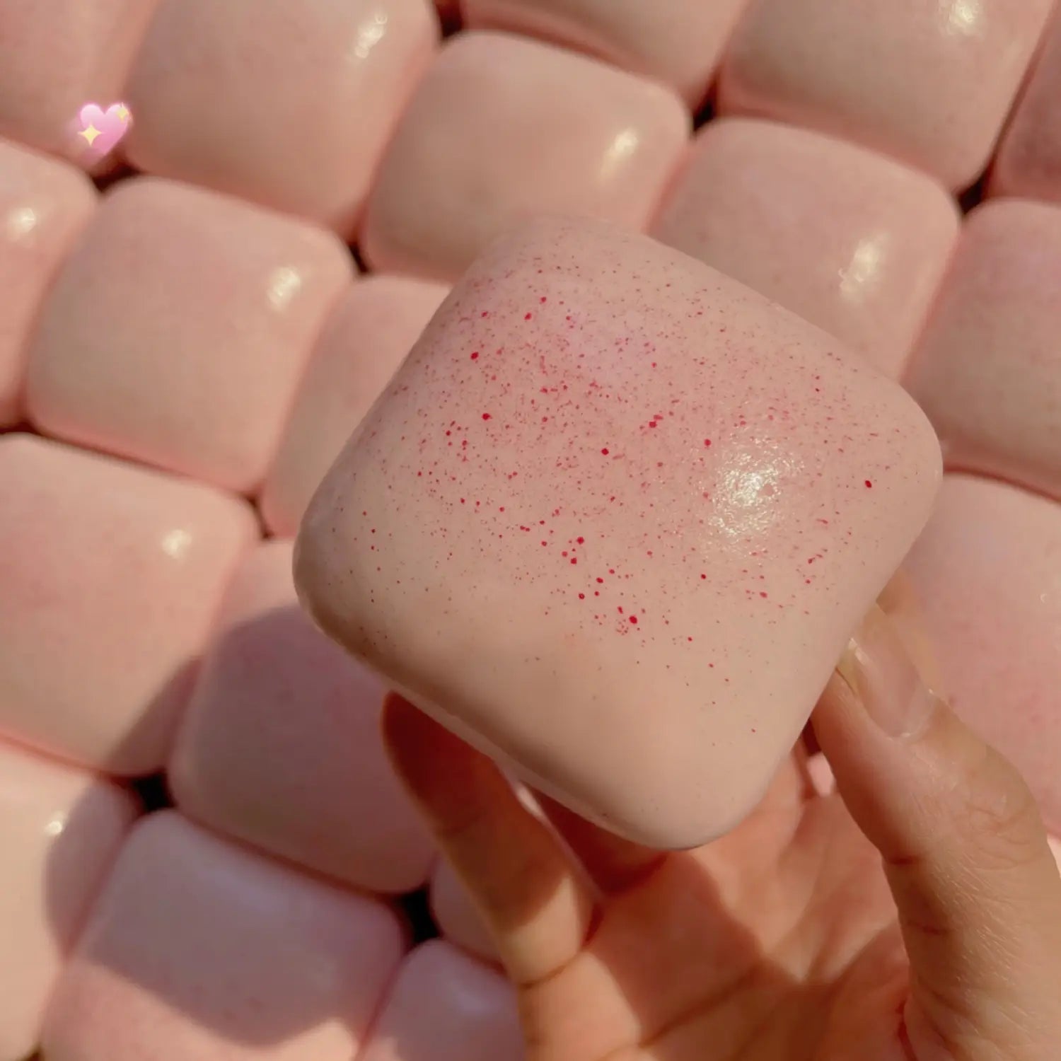 mini toast à dégagement lent, jouet sensoriel d’agitation, de forme carrée et rose tendre, avec une texture légèrement pailletée et de toutes petites mouchetures rouges, présenté de face.