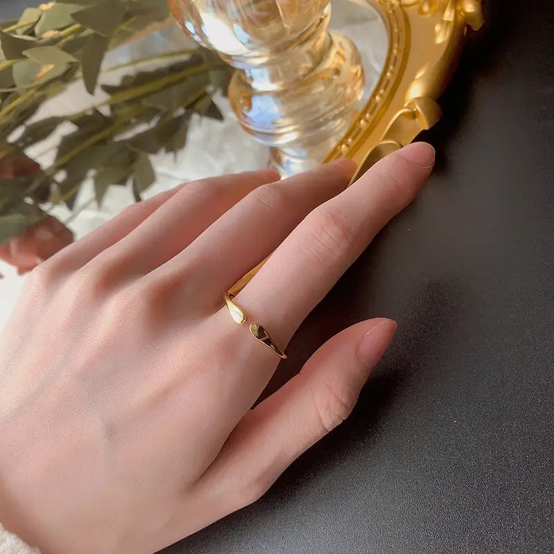 Un delicado anillo apilable de plata de ley con forma de gota, con un diseño minimalista que presenta una banda alargada y un pequeño acento en forma de corazón de oro.