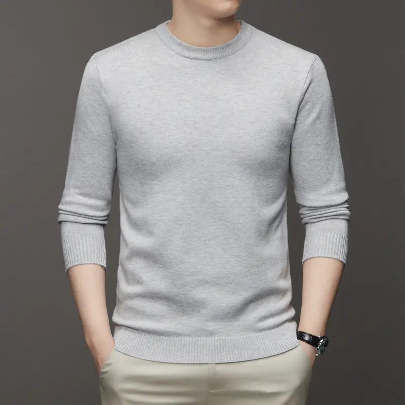 Ein hellgrauer klassischer Herren-Strickpullover mit Rundhalsausschnitt mit langen Ärmeln sowie gerippten Bündchen und Saum.