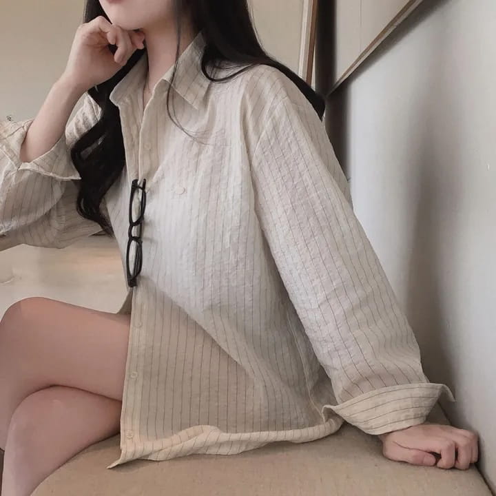 A loose-fitting striped long sleeve button down shirt in off-white with subtle vertical stripes and a relaxed collar offers a versatile style and standard thickness for comfortable wear.