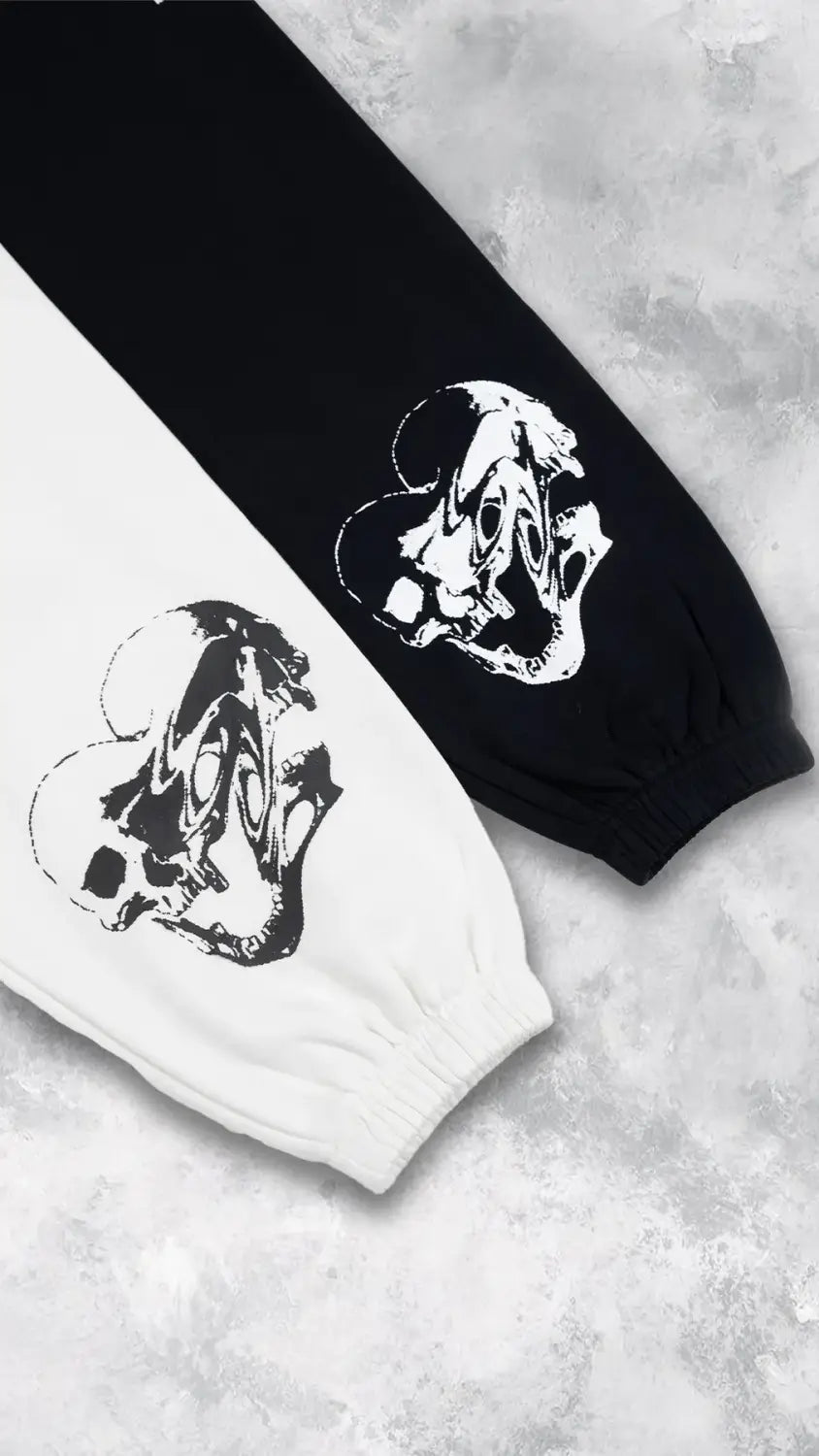 Pantalons d’entraînement graphiques pour hommes, sweatpants d’entraînement, noirs et blancs, avec des graphismes de crâne stylisés audacieux sur les poignets, conçus pour un usage sportif.