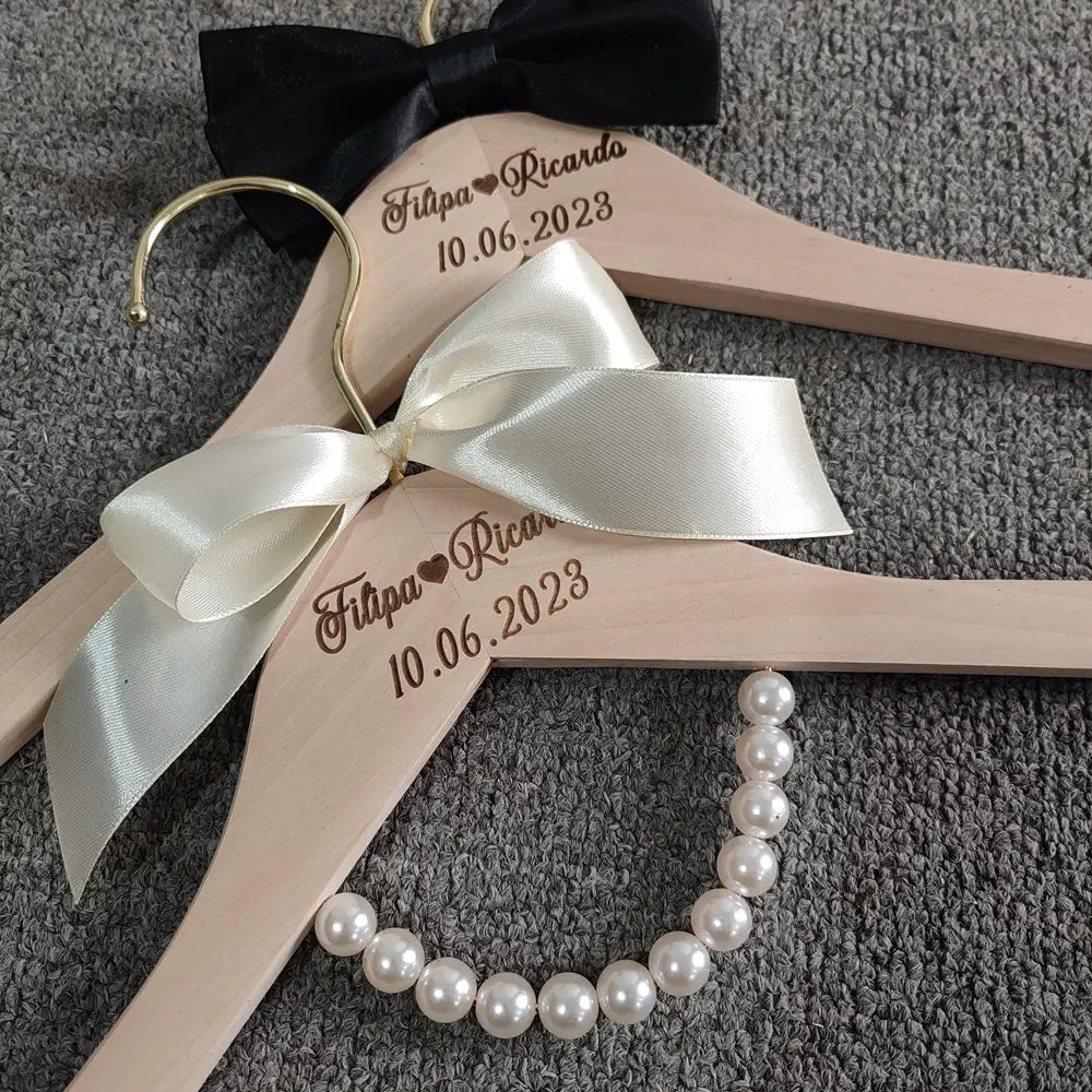Light wood personalized wedding dress hanger with cream satin bow and custom engraving filipa heart ricardo 10.06.2023 for bridal set.