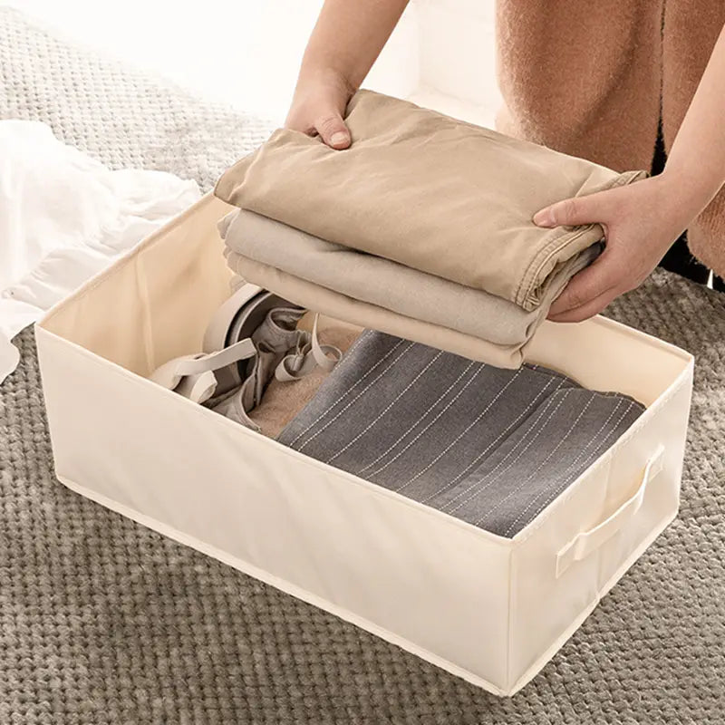 beigefarbene Stoff-Wäscheaufbewahrungsbox mit Griffen, ausgelegt für den Kleiderschrank und für Jeans.
