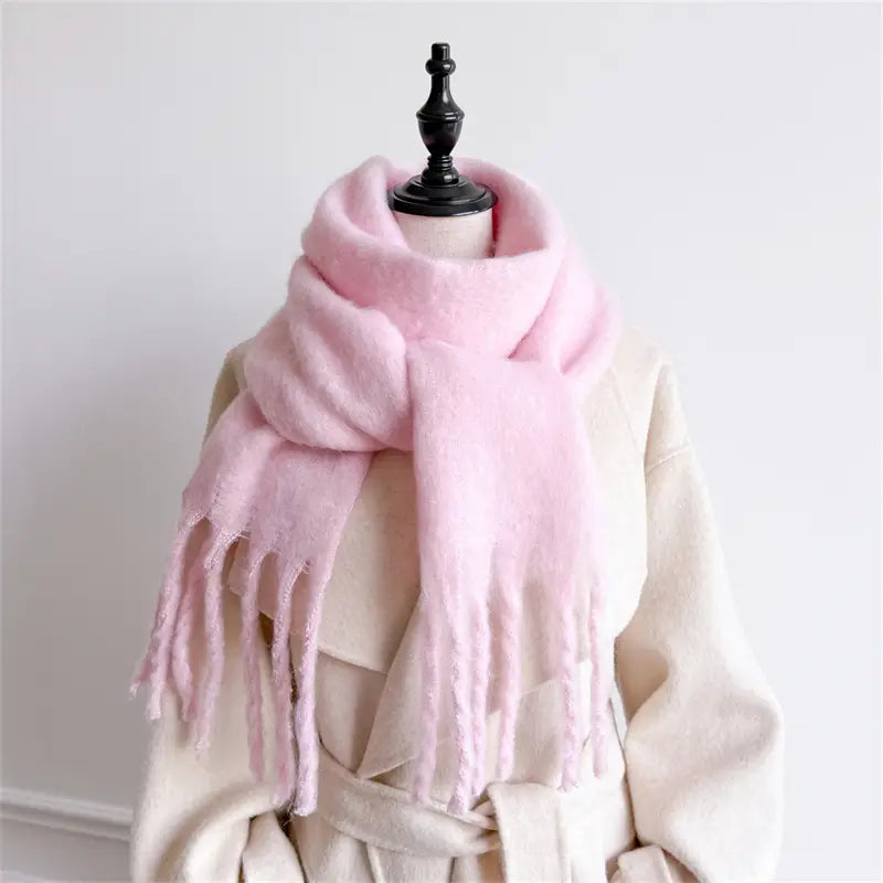 Ein weicher Pastellrosa-Schal für Damen mit Cashmere-ähnlichem Gefühl für den Winter mit flauschiger Textur und gefransten Kanten, elegant drapiert um den Hals einer Schaufensterpuppe.