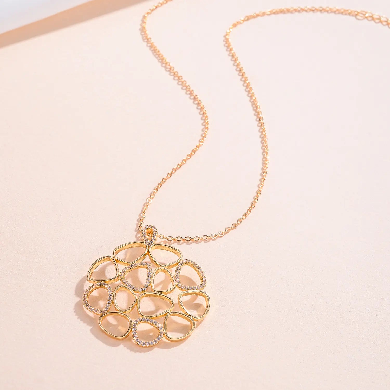 Collar con dije tipo lágrima dorado para mujer con una cadena delicada con acabado dorado e un dije intrincado de calado que presenta múltiples marcos con forma de lágrima delimitados con piedras transparentes brillantes.