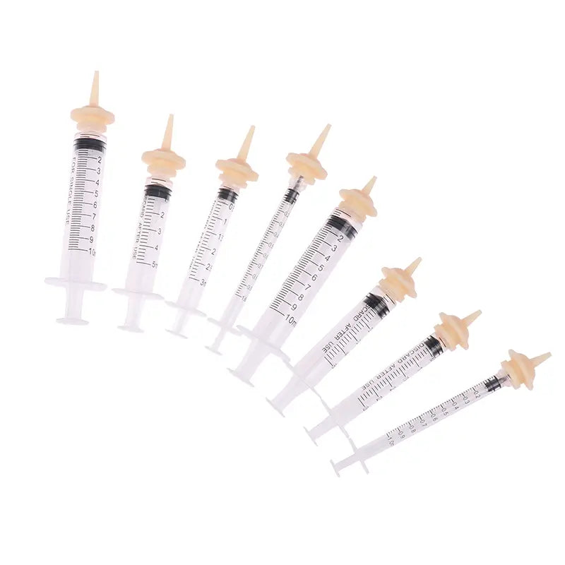 Set of clear plastic pet feeding syringes with beige caps and black measurement markings available in 3ml 5ml and 10ml silicone nipple sizes.
