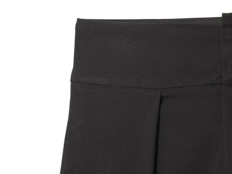 Pantalons noirs taille haute plissés à jambes évasées, avec une ceinture lisse et structurée, adaptés à une tenue formelle ou décontractée.